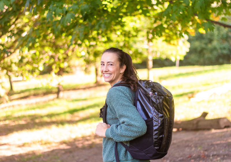 woman walking in the park with a black backpack