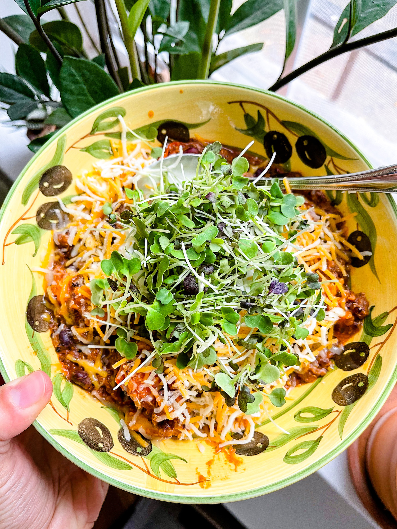 Bowl of chili topped with cheese and microgreens
